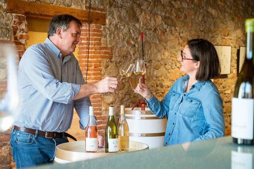 Two people toasting with wine glasses in a rustic cellar with wine bottles and barrels. 1