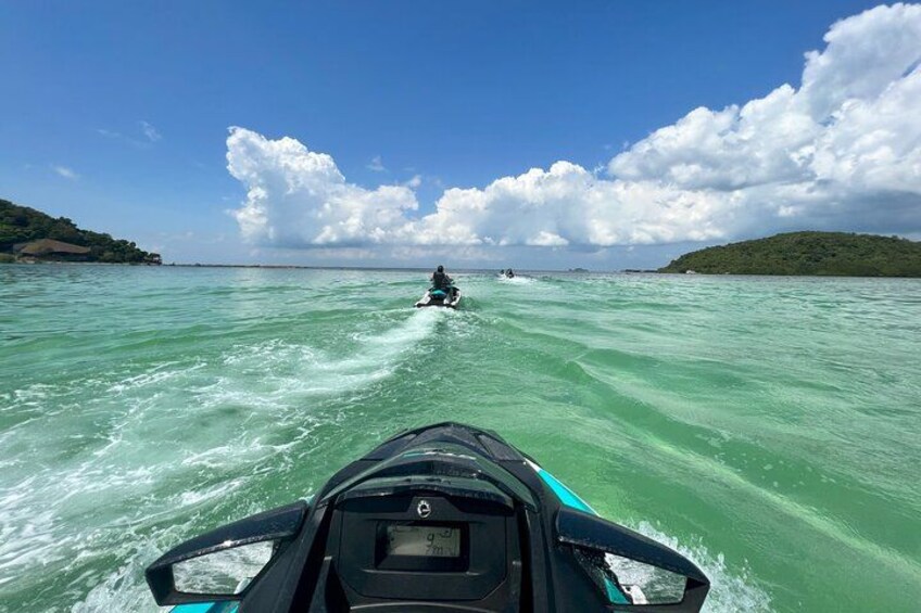 Un jet ski sur une eau turquoise, sous un ciel dégagé, avec une terre lointaine à l’horizon. 1