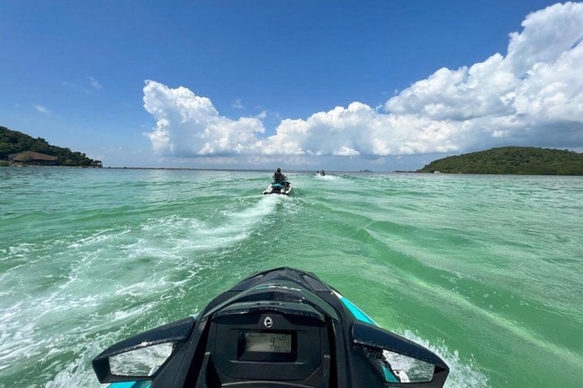 A jet ski on turquoise water with a clear sky and distant land. 1