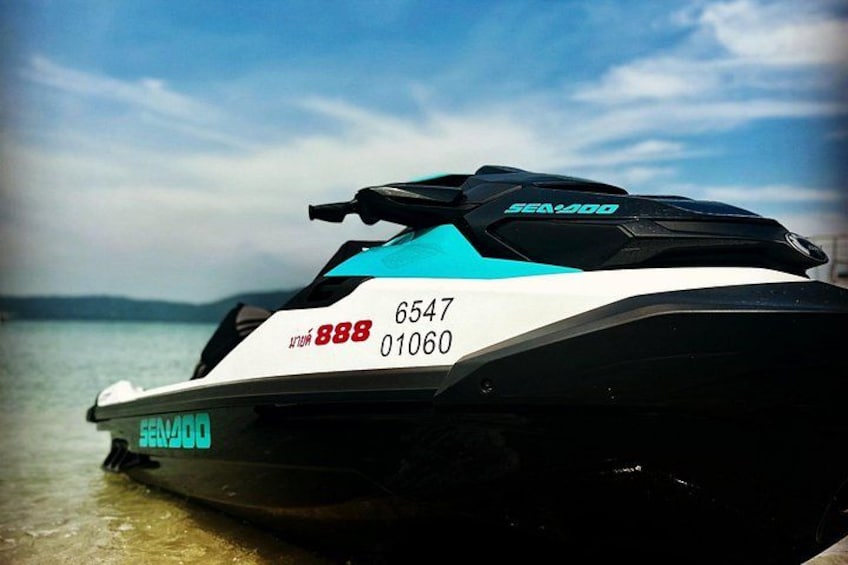 A Sea-Doo jet ski with the number 6547 and 888 on the side, parked on a body of water with a clear sky in the background. 3
