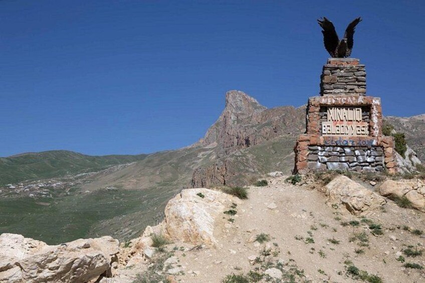 A mountain peak with a stone monument featuring an eagle sculpture and inscriptions. 4