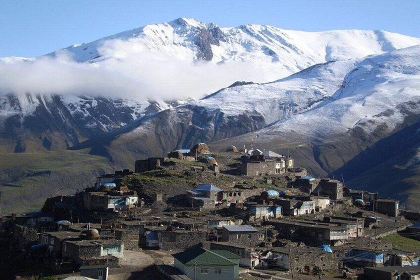 A snow-capped mountain, a village with buildings, and a clear sky. 5