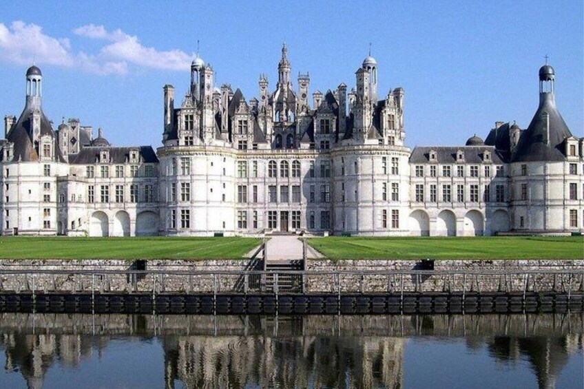 A grand château with multiple towers and a reflective water body in front. 3