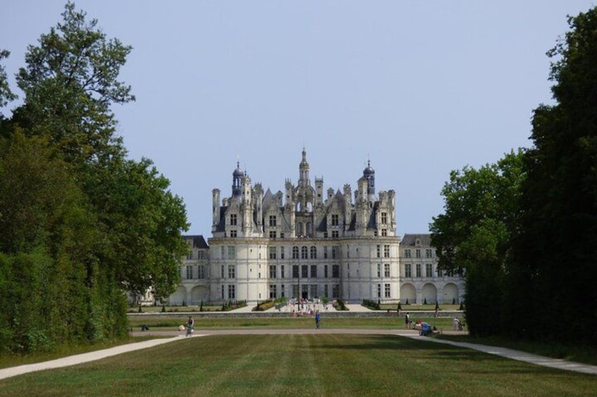 Un grand bâtiment historique à la façade symétrique, entouré de pelouses et d’arbres bien entretenus. 2