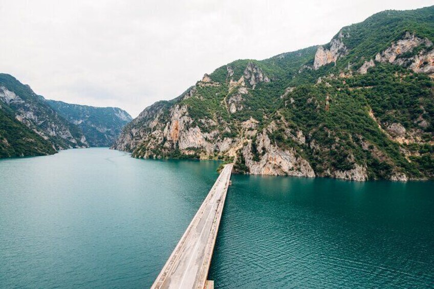 A wooden pier extending into a calm lake surrounded by steep, rocky cliffs. 2
