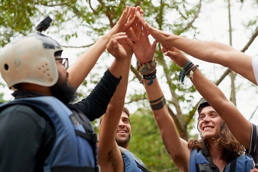 A group of people in a circle, wearing helmets and vests, raising their hands together. 4