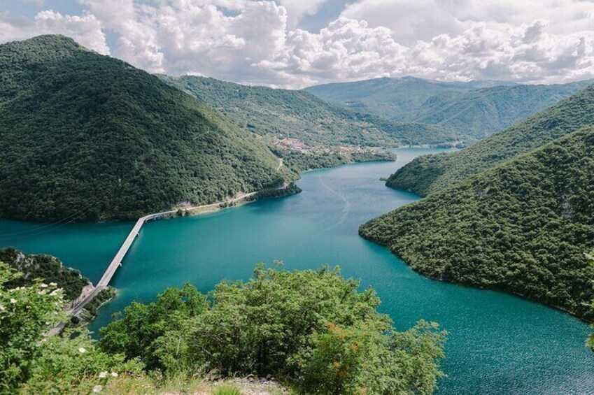 A turquoise lake surrounded by lush green hills. 3