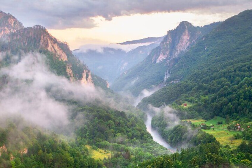 A valley with a river, mountains, and a small settlement. 3