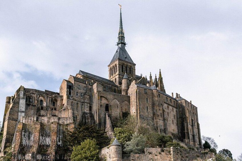 Eine große historische Kathedrale mit einem hohen Turm, umgeben von Steinmauern und Vegetation. 1