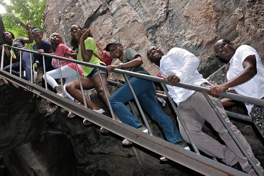 A group of people climbing a metal staircase in a rocky area. 1