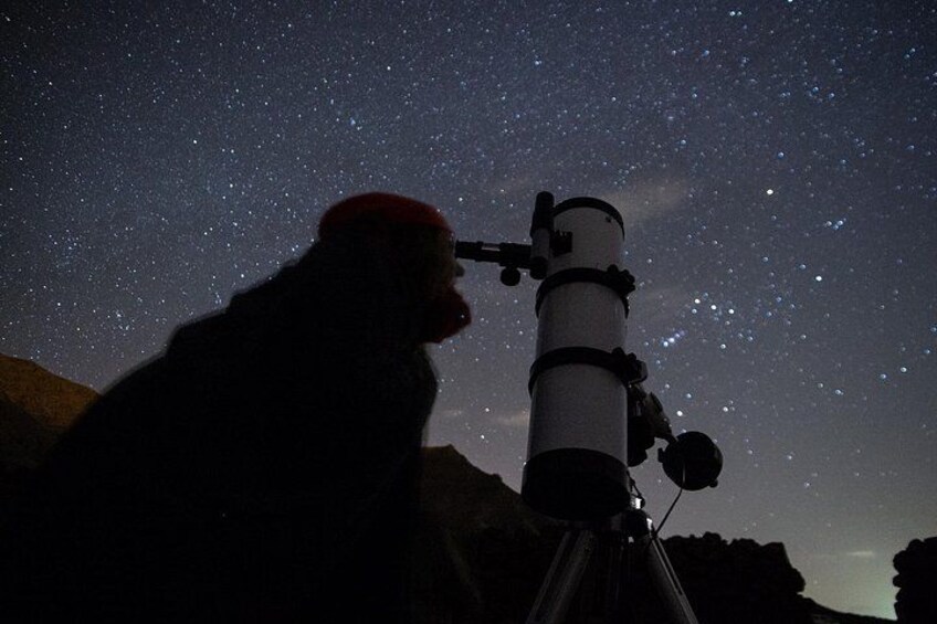 A person using a telescope under a starry night sky. 1