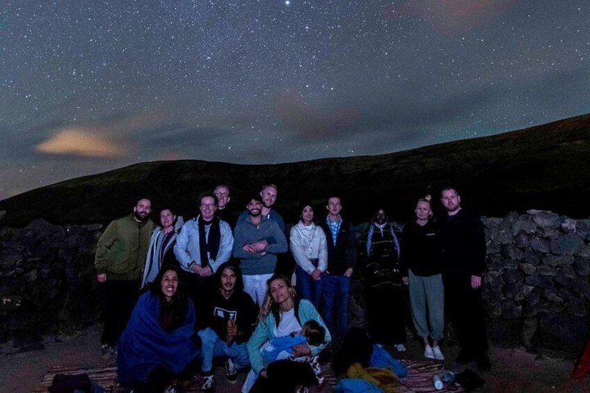 A group of people posing under a starry sky with a stone wall in the background. 5
