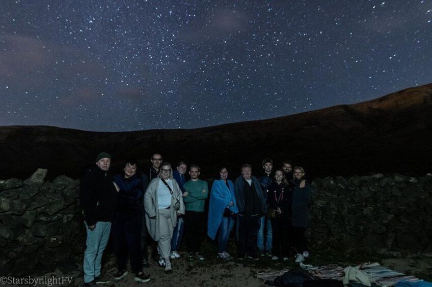 A group of people standing in a rocky area under a starry night sky. 2