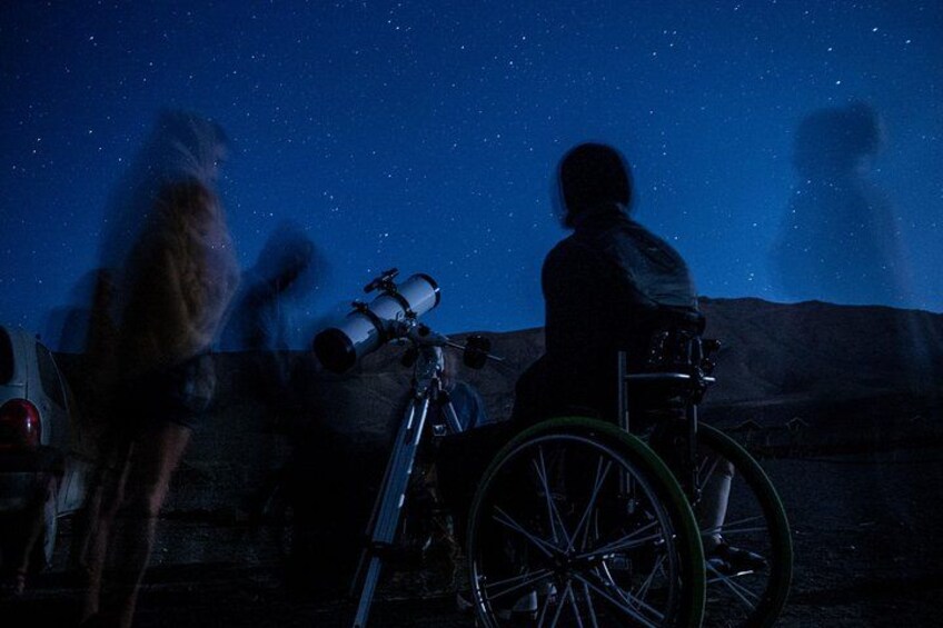 A person in a wheelchair observing the night sky through a telescope. 4