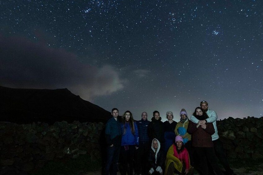 A group of people standing on a rocky terrain under a starry night sky. 2