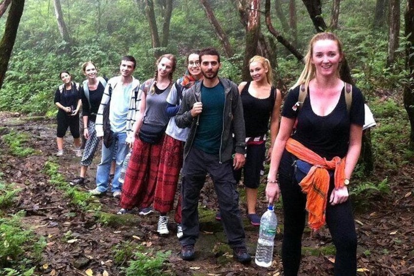 A group of people hiking in a forested area with a water bottle on the ground. 4