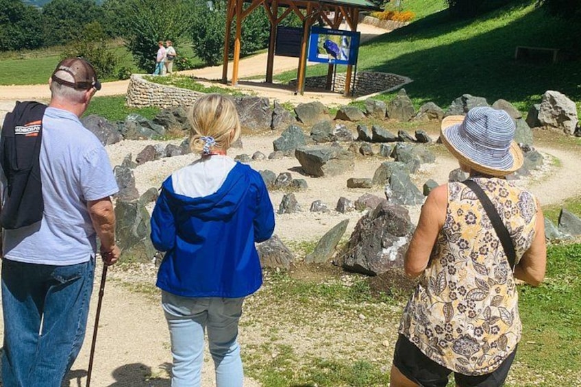 A group of people walking on a path with rocks and a wooden structure in the background. 2