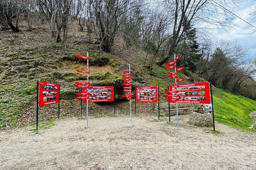 A dirt path with red directional signs and informational boards. 5