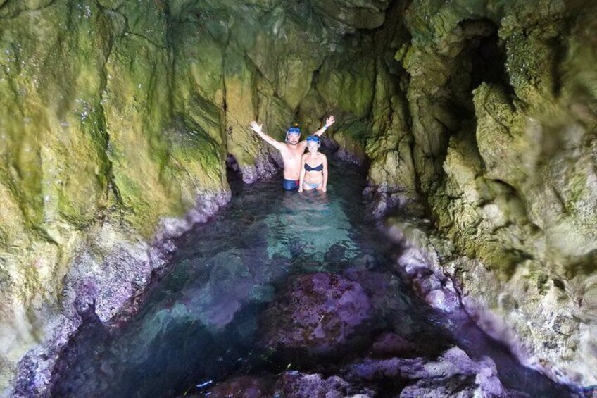 A person standing in a cave with water, surrounded by rocky walls. 5