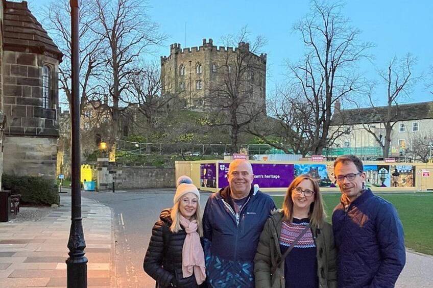 A group of people standing in front of a castle-like structure with a banner in the background. 4
