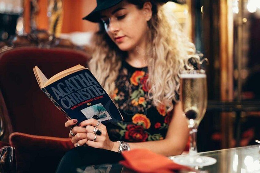 Una persona leyendo un libro titulado 'Agatha Christie' en un ambiente interior con poca luz. 3
