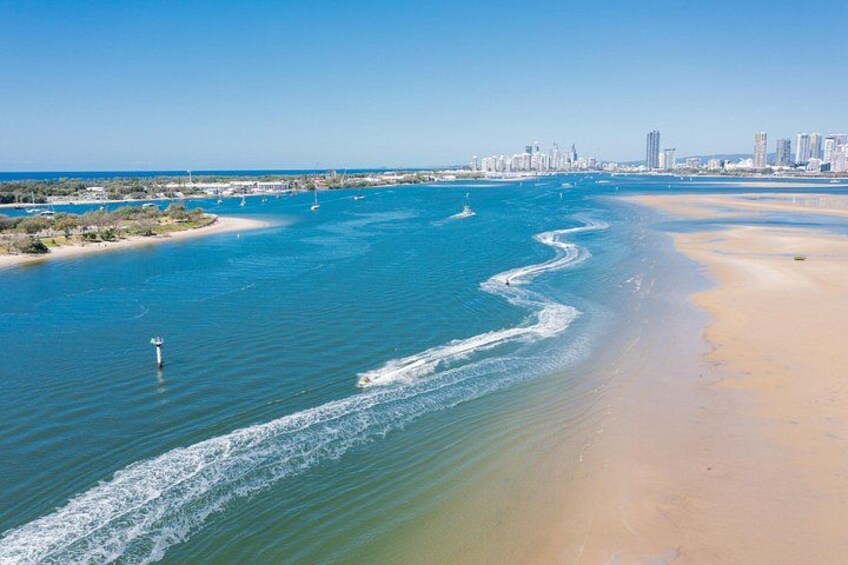 A coastal city with a wide beach, clear blue waters, and a distant skyline. 2