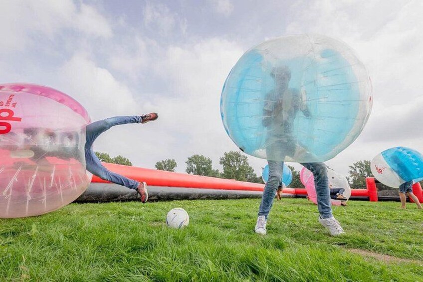People playing with large inflatable balls on a grassy field. 3