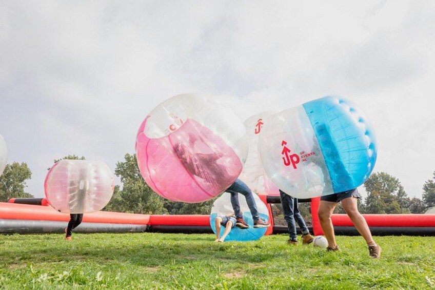 People playing with large inflatable balls in a grassy field. 1