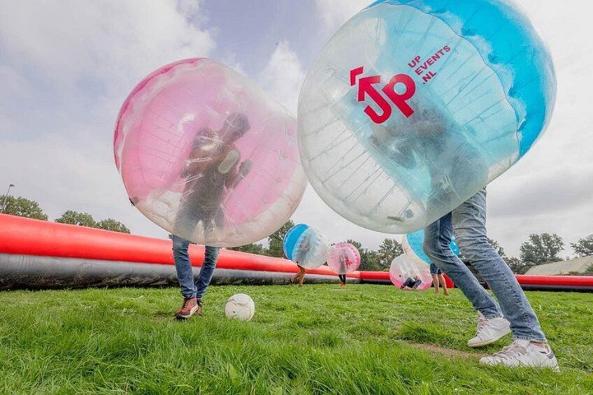 People playing with large inflatable balls in a grassy field. 2
