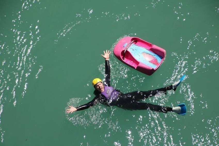 A person floating on water with a kayak nearby. 5