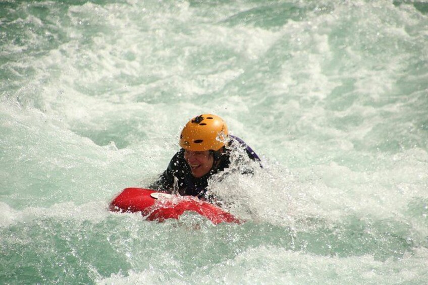 A person in a yellow helmet riding a red kayak in turbulent water. 2