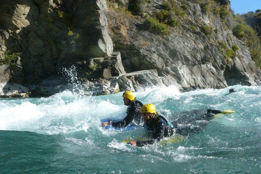 Dos personas kayakendo en un río con imponentes riscos al fondo. 2