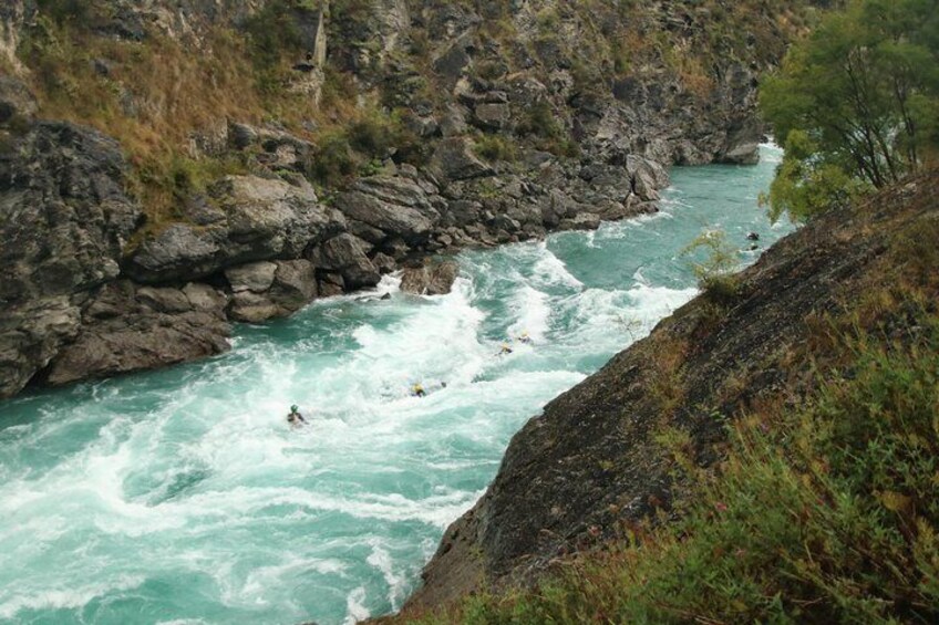 A river with white water rapids, surrounded by rocky cliffs and sparse vegetation. 2