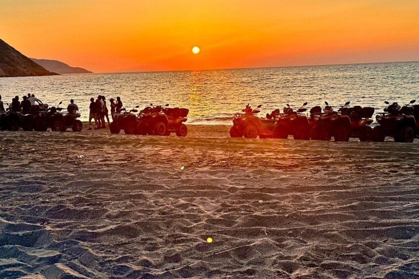 Solnedgang over en strand med parkerede ATV'er. 3