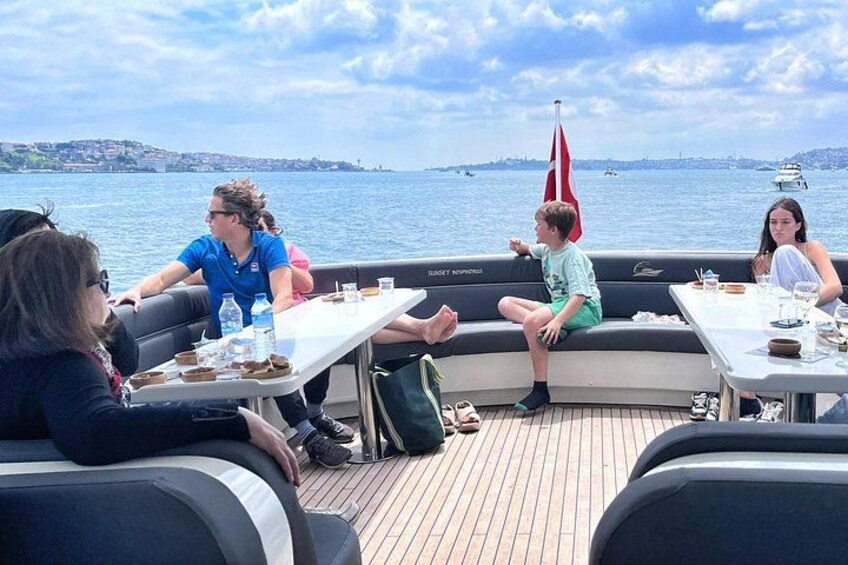 Un gruppo di persone sta cenando su una barca con vista sull'acqua e una bandiera. 4