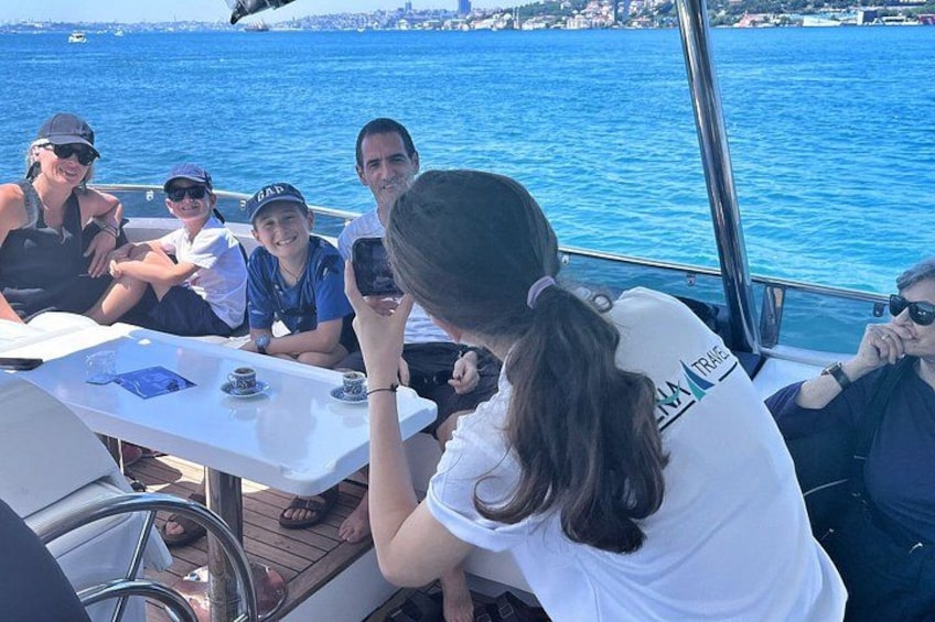 Un gruppo di persone su una barca con un tavolo, l'acqua e una costa in lontananza. 2