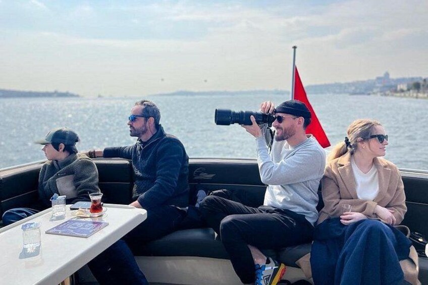 Una barca con tre persone, una delle quali sta scattando una foto, e una bandiera rossa sullo sfondo. 5