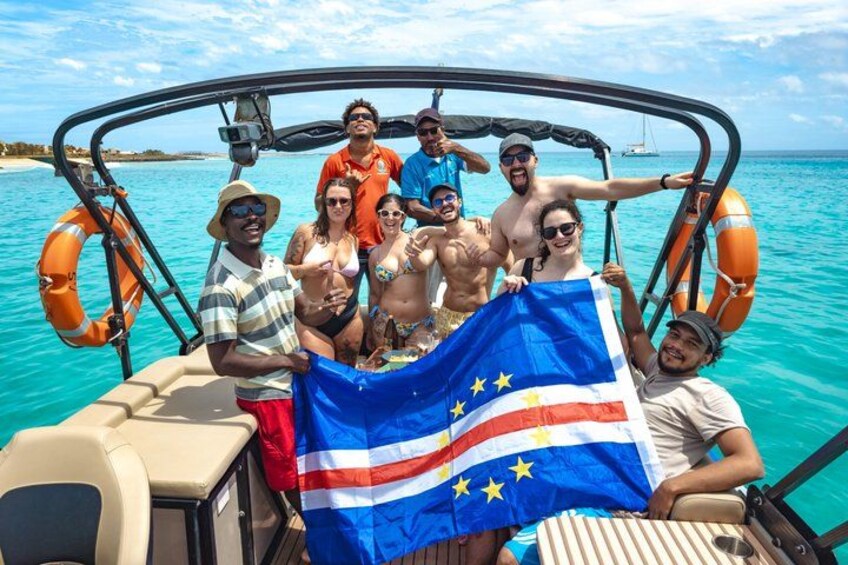 Eine Gruppe von Menschen auf einem Boot mit einer Flagge, Rettungsringen und ruhiger See. 3
