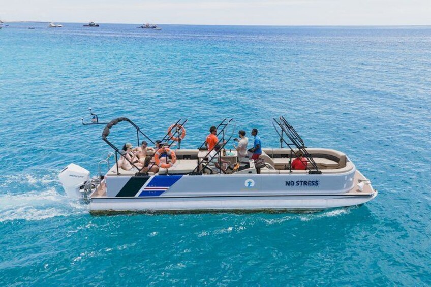 Ein Boot mit Personen fährt durch klares, blaues Wasser. 1