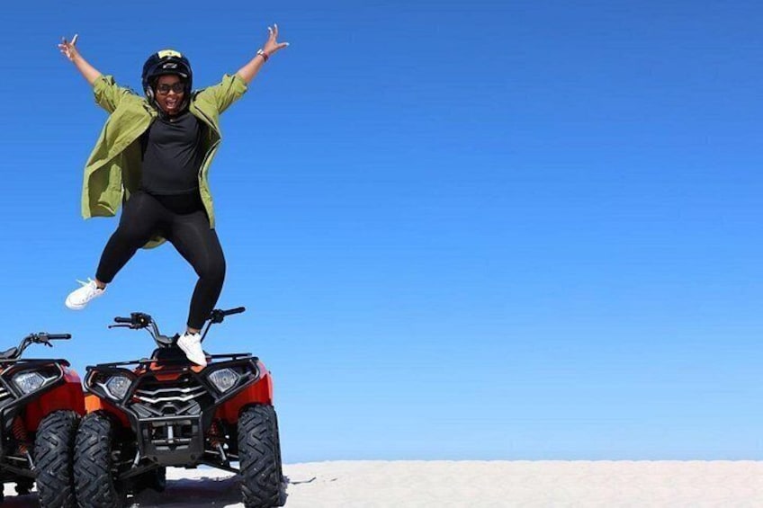 A person jumping on a quad bike in a desert landscape. 5