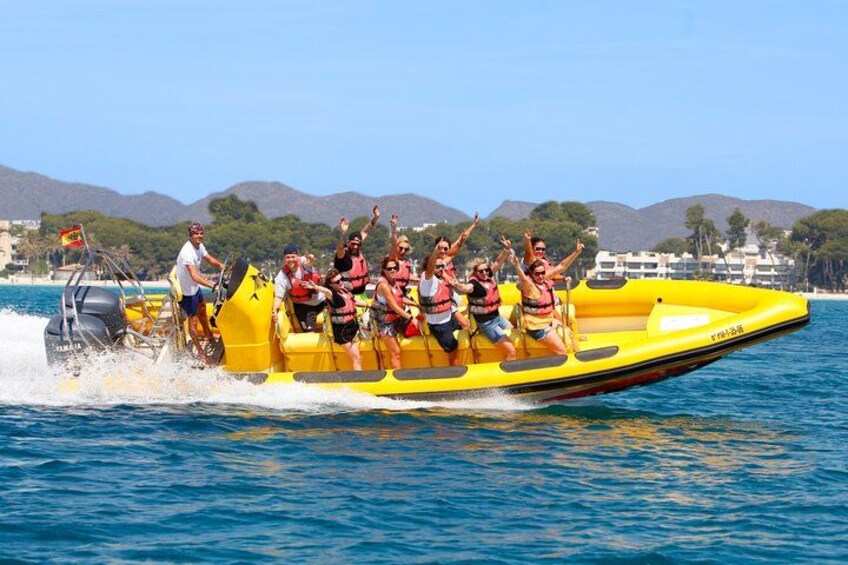 Un bateau pneumatique jaune, transportant des passagers portant des gilets de sauvetage, navigue sur une étendue d’eau, avec des montagnes en arrière-plan. 1