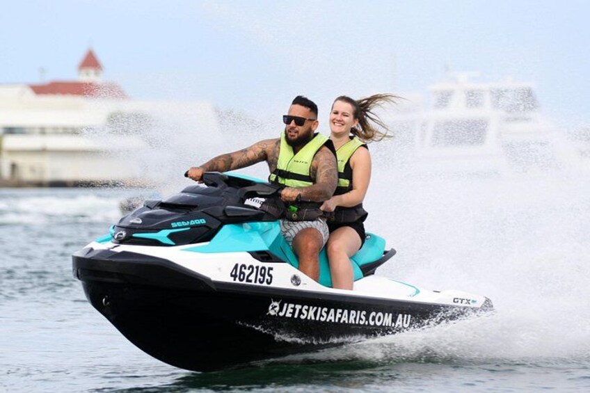 A jet ski with two people wearing life jackets, water splashing around them. 1