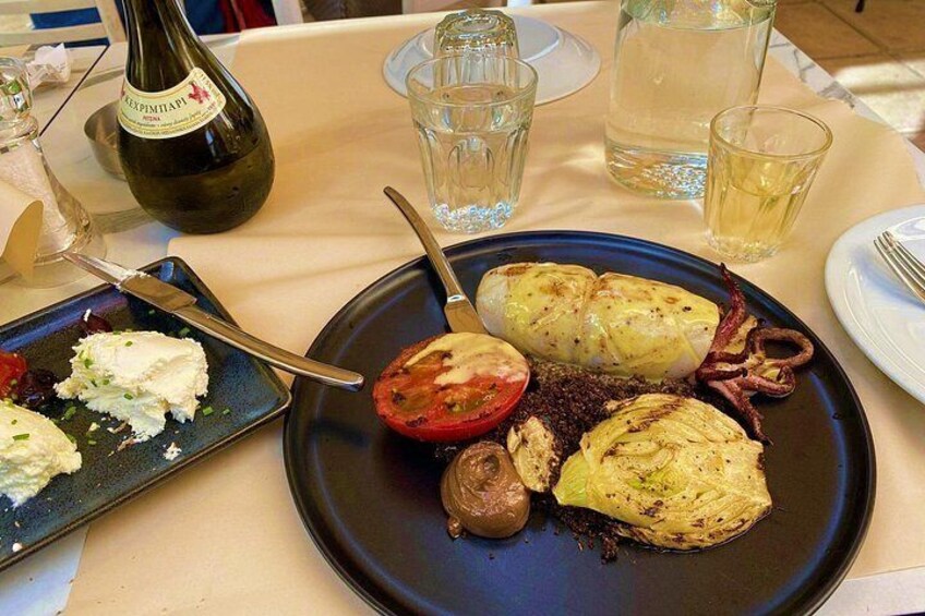 A plate with stuffed vegetables, a bottle of wine, and glasses on a table. 2