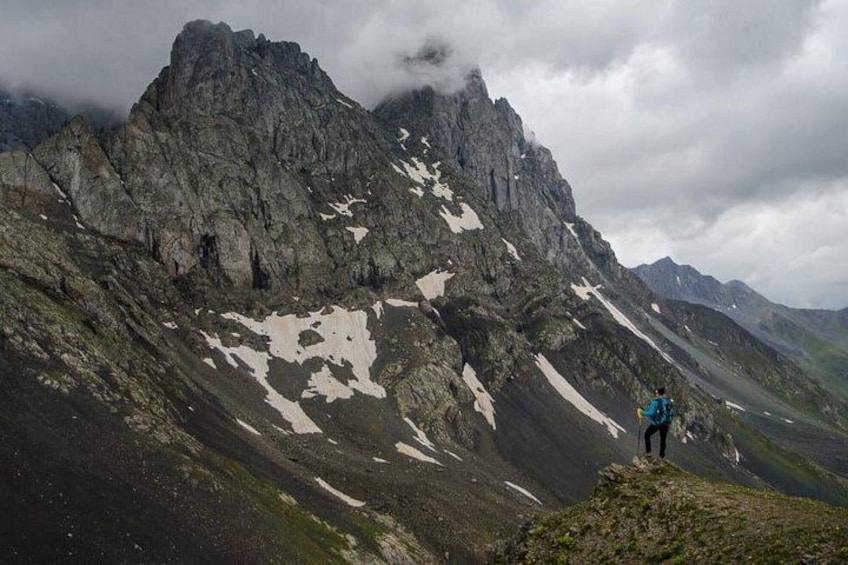A mountainous landscape with a person standing on a ridge. 1