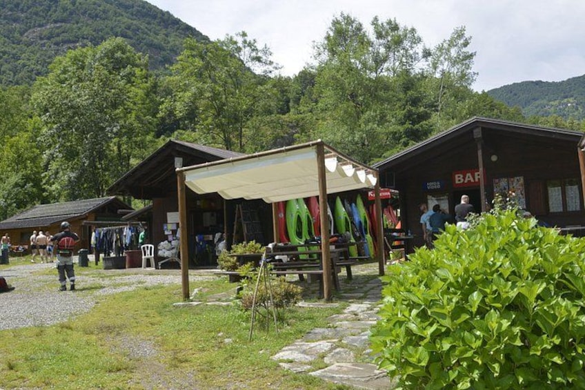 Una cabaña de montaña con asientos al aire libre, kayaks y un bar. 3