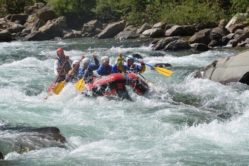 Un grupo de personas haciendo rafting en un río con rocas y rápidos. 4