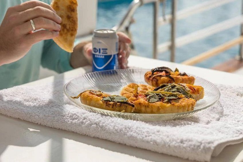 A person holding a can and a piece of flatbread, with a plate of food in the foreground. 2