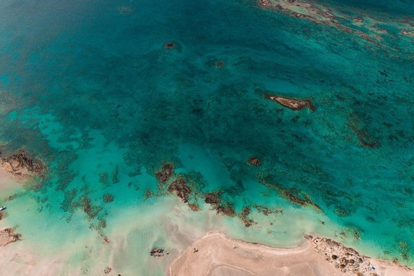 A turquoise sea with coral reefs and a sandy beach. 1