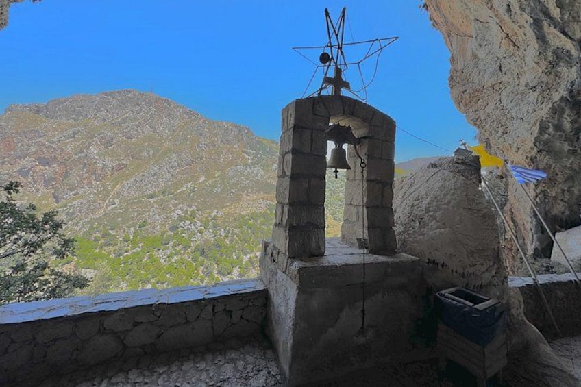 A bell tower with a stone structure, a flag, and a mountainous landscape in the background. 4