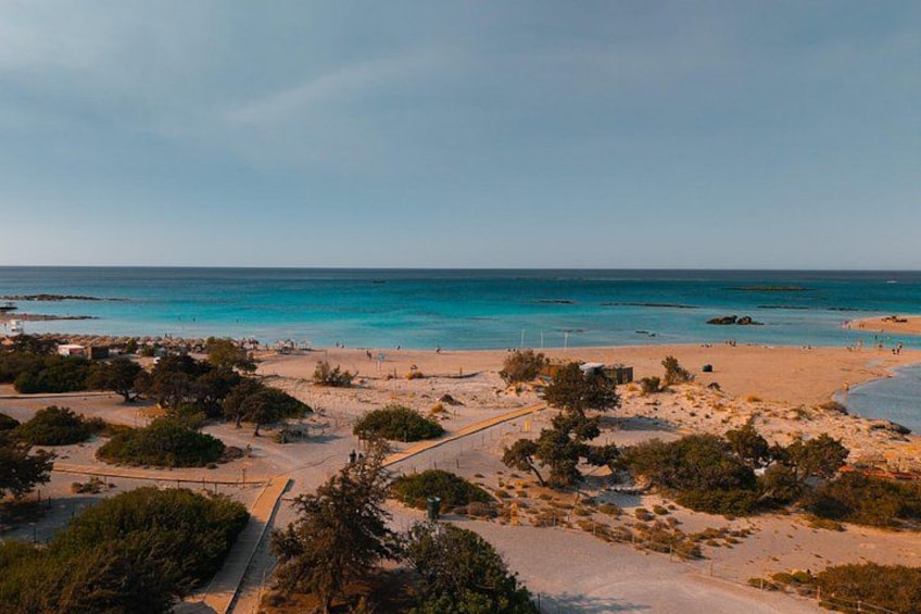 A coastal landscape with a sandy beach, sparse vegetation, and a clear sky. 2